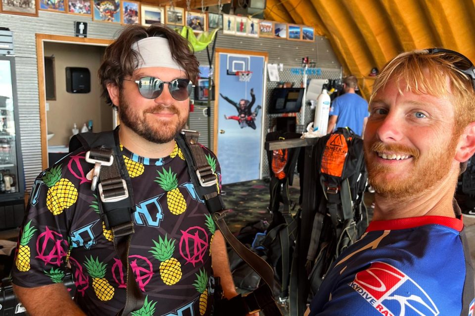 younger man with headband and sunglasses gets geared up for a skydive