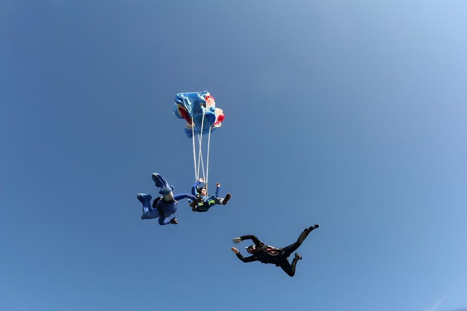 student deploys canopy while two instructors look on to give instruction on learning how to skydive