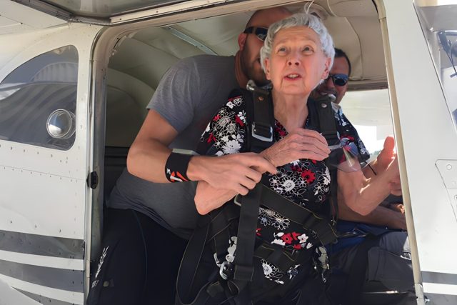 older woman looks pensive before jumping out of skydiving aircraft