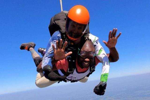 male tandem student smiles with eyes closed in skydiving freefall