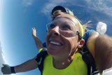 woman in yellow shirt smiles while freefalling