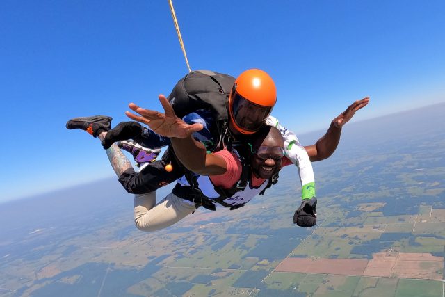 male tandem student smiles with eyes closed in skydiving freefall
