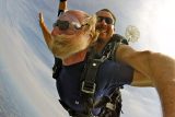 older gentleman's beard blows back in his face while skydiving at 120mph