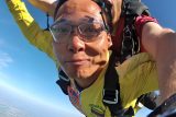 man in yellow jumpsuit experiences the thrill of a tandem skydive at OZARKS Skydive Center