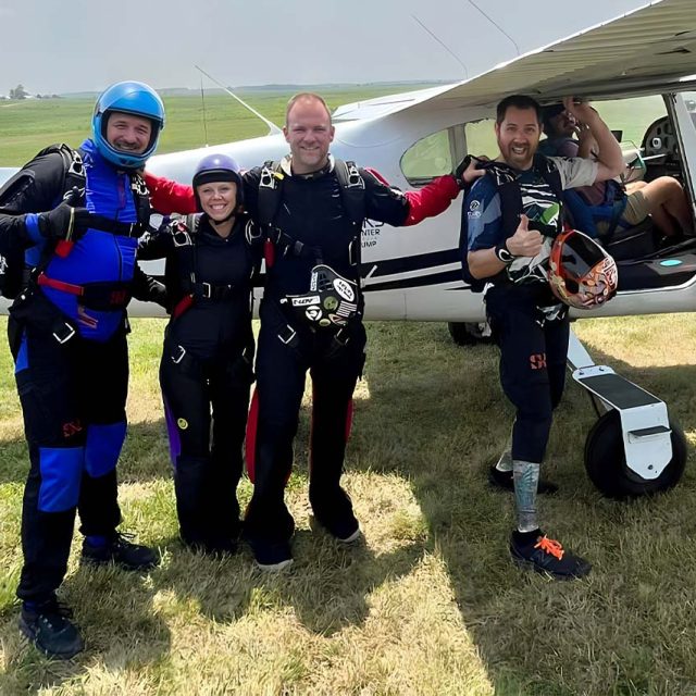 4 fun jumpers smile before getting into skydiving aircraft