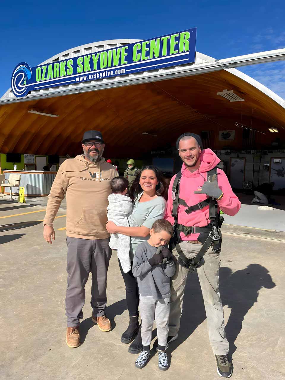 family poses in front of OZARKS Skydive Center sign