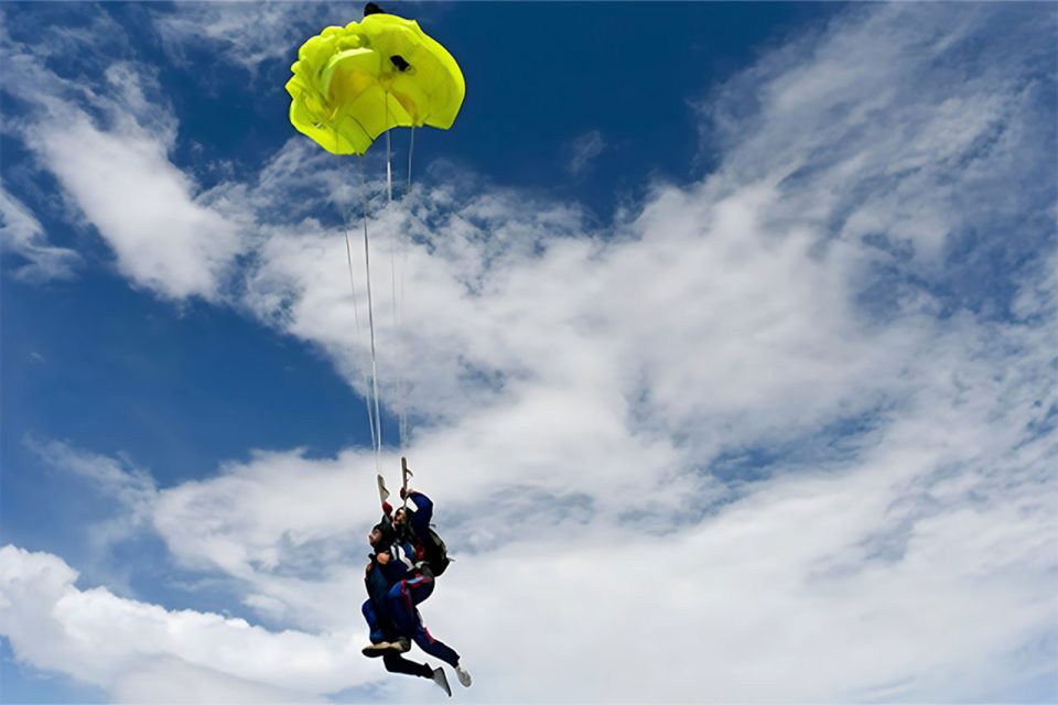 tandem student prepares for yellow canopy to deploy