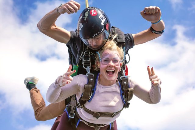 young woman in pink long sleeved t-shirt rocks out her tandem skydive