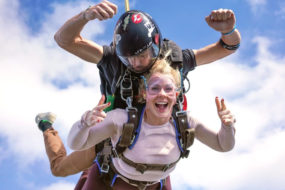young woman in pink long sleeved t-shirt rocks out her tandem skydive