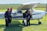 young woman waves and smiles before boarding the skydiving aircraft