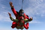 woman in gray jumpsuit tandem skydives with instructor in red jumpsuit
