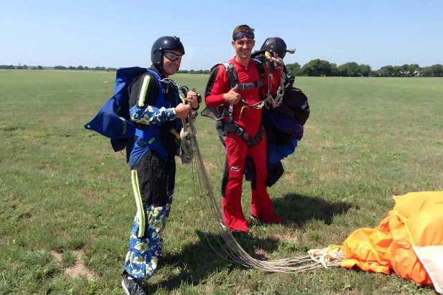 2 fun jumpers grab parachutes from landing area after a fun jump