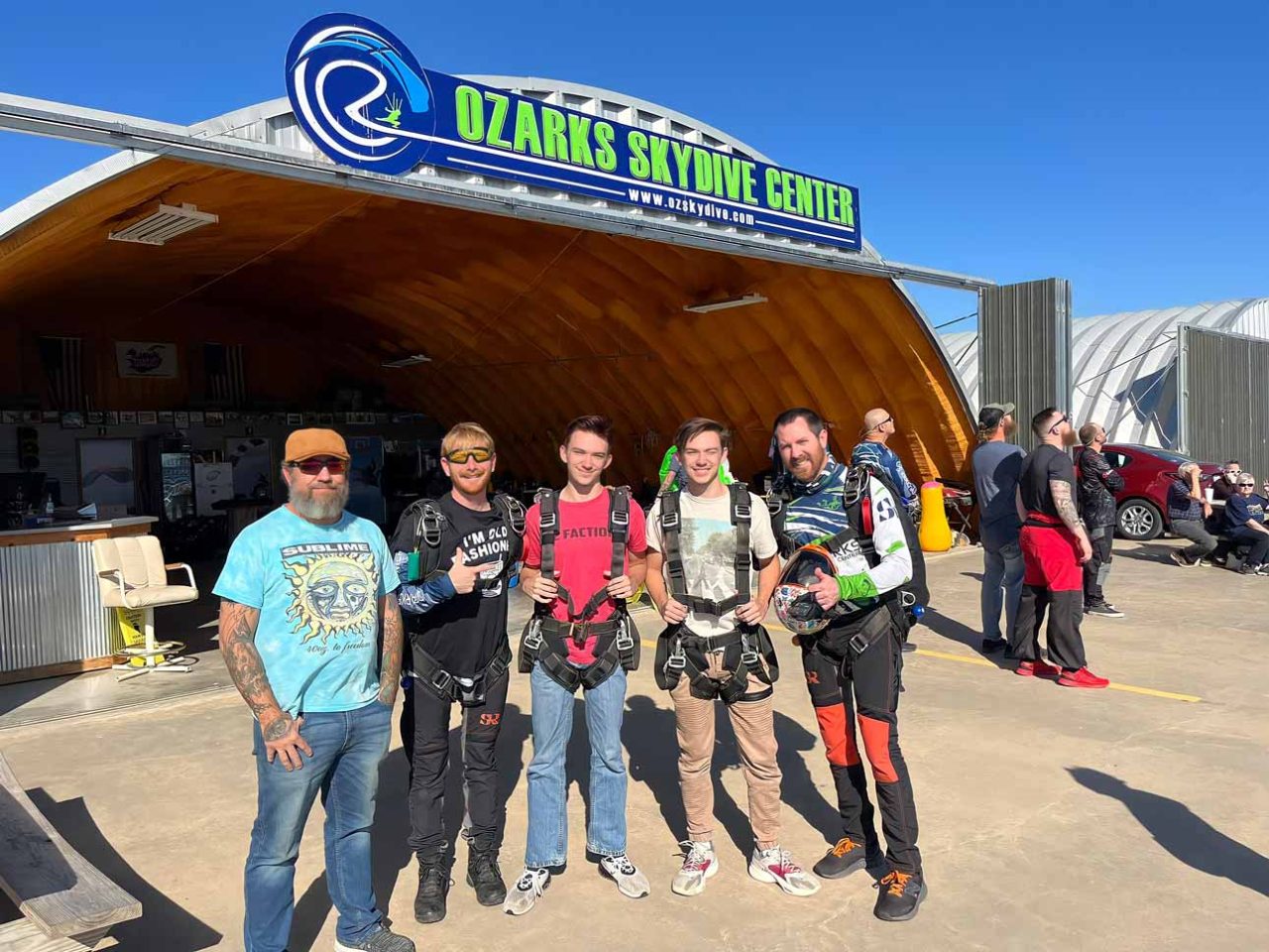 group of young men pose in front of OZARKS Skydive Center sign before skydiving