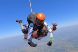 male tandem student smiles with eyes closed in skydiving freefall