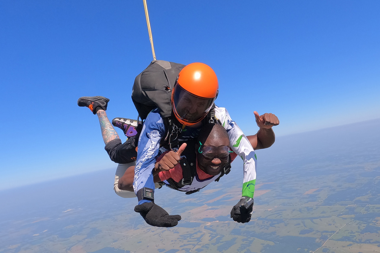 male tandem student smiles with eyes closed in skydiving freefall