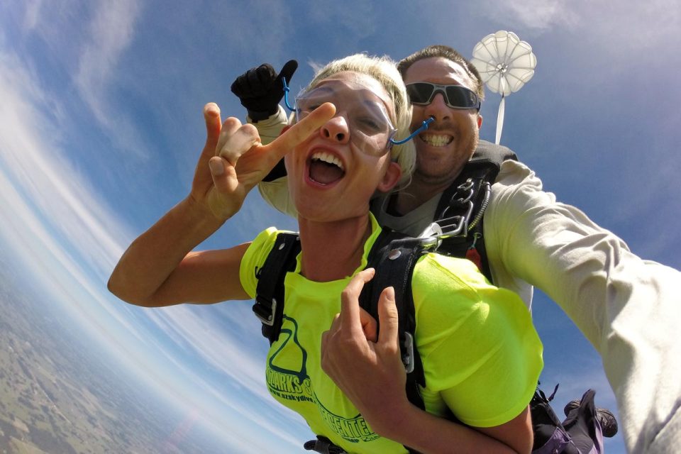 woman in bright yellow t-shirt smiles while experiencing freefall